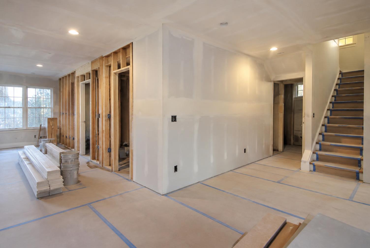 Tidy residential remodeling jobsite with protected floors, organized materials, and clean drywall work