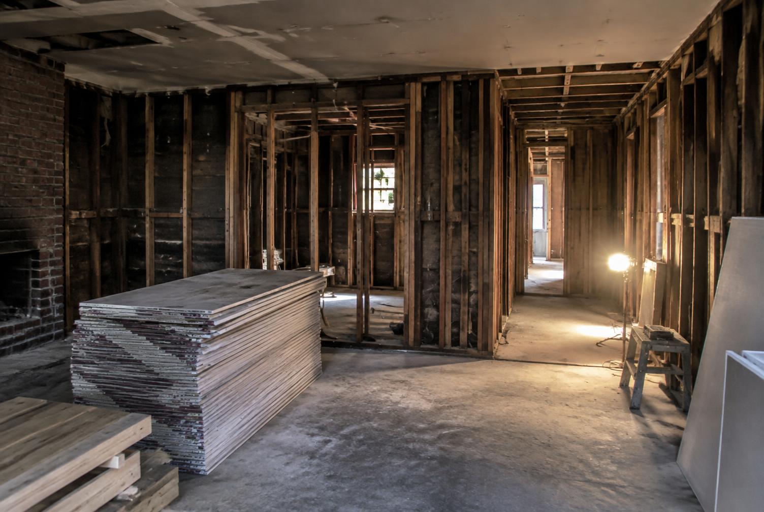 Fire-damaged room during reconstruction with smoke-stained drywall removed and framing exposed